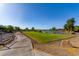 Scenic golf course view with a serene lake and lush green fairway under a clear blue sky, showcasing the community's amenities at 20283 N 273Rd Ave, Buckeye, AZ 85396