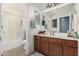 Well-lit bathroom featuring wood vanity, shower-tub combo and neutral tile floor at 2048 S Martingale Rd, Gilbert, AZ 85295