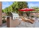 Outdoor kitchen, BBQ, two lounge chairs with an umbrella in the backyard at 22634 N 47Th Pl, Phoenix, AZ 85050