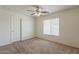 Well-lit bedroom with a ceiling fan, neutral carpeting, and a window with bright light at 28054 N Jade St, San Tan Valley, AZ 85143