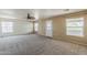 Spacious living room featuring neutral carpeting, ceiling fan, and natural light from multiple windows at 28054 N Jade St, San Tan Valley, AZ 85143