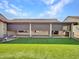 Backyard includes green turf lawn, covered patio with shades, and views of nearby house roofs at 3702 N 160Th Ave, Goodyear, AZ 85395