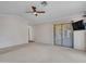 Spacious carpeted living room with sliding glass doors, ceiling fan, and a mounted television at 3702 N 160Th Ave, Goodyear, AZ 85395