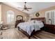 Main bedroom with wood-look floors, ceiling fan, and arched windows provides a light-filled space at 38560 N Joann Way, San Tan Valley, AZ 85140