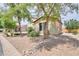 Well-maintained home featuring desert landscaping, a rock-lined garden, and mature trees at 40232 W Marion May Ln, Maricopa, AZ 85138