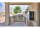 Covered outdoor kitchen featuring a stainless steel grill, countertop space, sink, and mini-refrigerator at 40232 W Marion May Ln, Maricopa, AZ 85138