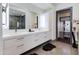 Modern bathroom featuring double sinks, a large mirror, textured wall and doorway to vanity area at 4422 N 75Th St # 8004, Scottsdale, AZ 85251
