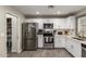 Bright kitchen with stainless steel appliances, white cabinetry, and wood-look flooring, perfect for cooking at 4549 W Poinsettia Dr, Glendale, AZ 85304