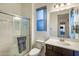 Contemporary bathroom featuring a glass-enclosed shower, vanity, and toilet, enhanced by a blue-tinted window at 4822 N Barranco Dr, Litchfield Park, AZ 85340