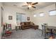 Cozy living room with plush gray carpet, brown sofa, ceiling fan, and natural light from multiple windows at 4822 N Barranco Dr, Litchfield Park, AZ 85340