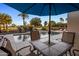 Scenic pool area with dining table, chaise lounges, lush landscaping, and a beautiful backdrop of mature trees at 4822 N Barranco Dr, Litchfield Park, AZ 85340