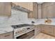 Modern kitchen featuring a stainless steel range, marble backsplash, and custom cabinetry at 6184 E Dusty Coyote Cir, Scottsdale, AZ 85266