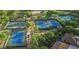 Aerial view of multiple tennis and pickleball courts, pool, and clubhouse surrounded by lush trees at 6184 E Dusty Coyote Cir, Scottsdale, AZ 85266