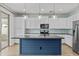 Modern kitchen boasts white cabinetry, a blue island, stainless steel appliances and stylish pendant lighting at 9727 E Torino Ave, Mesa, AZ 85212