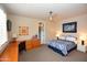 Cozy bedroom with a ceiling fan, desk area, and comfortable bed, complemented by natural light from the window at 9842 E Celtic Dr, Scottsdale, AZ 85260