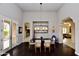 Elegant dining room with dark wood floors, modern lighting fixture, and views into kitchen and living spaces at 9842 E Celtic Dr, Scottsdale, AZ 85260
