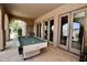 Covered patio with billiard table and multiple doorways, offering a relaxed space for entertaining guests at 9842 E Celtic Dr, Scottsdale, AZ 85260