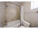 Bathroom featuring a shower-tub combo with stylish tan and white surround and white toilet at 10858 E Sahuaro Dr, Scottsdale, AZ 85259