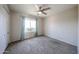 Neutral carpeted bedroom with a window, lighted ceiling fan and closet with folding door at 10858 E Sahuaro Dr, Scottsdale, AZ 85259