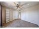 Spacious carpeted bedroom with ceiling fan, white built-in shelving, and closet with double doors at 10858 E Sahuaro Dr, Scottsdale, AZ 85259