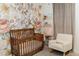 Floral Bedroom with a wooden crib, rocking chair, and floral accent wall at 14344 W Hackamore Dr, Surprise, AZ 85387