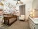 Floral Bedroom featuring a wooden crib, rocking chair, and white changing table at 14344 W Hackamore Dr, Surprise, AZ 85387