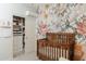 Bedroom showcasing a wooden crib beside a custom closet with shelves and drawers at 14344 W Hackamore Dr, Surprise, AZ 85387