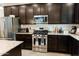Modern kitchen featuring stainless steel appliances, granite countertops, and dark wood cabinets at 14344 W Hackamore Dr, Surprise, AZ 85387