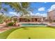 Large backyard featuring a pool, putting green, desert landscaping and mature trees at 14426 W Becker Ln, Surprise, AZ 85379