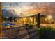 Beautiful backyard with a sparkling pool, covered patio, and lush desert landscaping under a vibrant sky at 14426 W Becker Ln, Surprise, AZ 85379