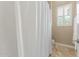 Well-lit bathroom showcasing tile floors, plantation shutters, neutral walls and a stylish shower curtain at 14426 W Becker Ln, Surprise, AZ 85379
