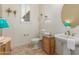 Bright bathroom with decorative wall shelves, pedestal sink, and decorative turquoise lamp at 14426 W Becker Ln, Surprise, AZ 85379