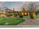 Beautifully landscaped home with lush lawn, desert plants, and a detached garage at twilight at 14426 W Becker Ln, Surprise, AZ 85379