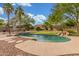 Lush backyard with a unique freeform pool with rock waterfall, putting green, and mature landscaping at 14426 W Becker Ln, Surprise, AZ 85379