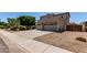 Beige two-story home with a three-car garage, desert landscaping, and a wide driveway at 15683 W Minnezona Ave, Goodyear, AZ 85395