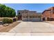 Beige two-story home featuring a three-car garage and low-maintenance desert landscaping at 15683 W Minnezona Ave, Goodyear, AZ 85395