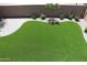 Aerial view of landscaped backyard with artificial turf, flower bushes, and brick paver accents at 20217 W Desert Bloom St, Buckeye, AZ 85326