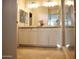 Well-lit bathroom with double sinks, vanity, tile floor, and open entryway at 20217 W Desert Bloom St, Buckeye, AZ 85326