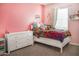 Bedroom features a bright decor, plush pillows, pink walls, and a window with natural light at 20217 W Desert Bloom St, Buckeye, AZ 85326
