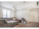 The spacious living room features plush gray sectional sofa and white trim and access to natural light at 20217 W Desert Bloom St, Buckeye, AZ 85326