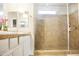 Bright bathroom featuring a double vanity, white cabinetry, tile floors, and glass enclosed shower at 20217 W Desert Bloom St, Buckeye, AZ 85326