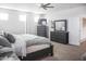 Bright main bedroom featuring neutral walls, carpet floors, ceiling fan, dresser, and ensuite access at 20217 W Desert Bloom St, Buckeye, AZ 85326
