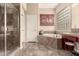 Bathroom featuring a tiled tub, glass shower, and decorative wall art, creating a serene and stylish space at 20532 W Summit Pl, Buckeye, AZ 85396