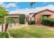 Charming front yard featuring lush lawn, mature palm trees, flowering bushes, and brick and stucco home exterior at 20532 W Summit Pl, Buckeye, AZ 85396