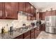Close-up shot of a well-equipped kitchen with granite countertops, stainless steel appliances, and dark wood cabinetry at 20532 W Summit Pl, Buckeye, AZ 85396