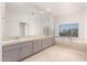 Bathroom with a large mirror, double sinks, neutral toned cabinets, and soaking tub next to a window at 22050 N 90Th St, Scottsdale, AZ 85255