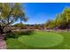 Putting green with desert landscaping, and mature trees providing privacy at 22050 N 90Th St, Scottsdale, AZ 85255