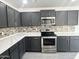 This kitchen offers stainless steel appliances, quartz countertops, and gray cabinetry at 22261 W Tonto St, Buckeye, AZ 85326