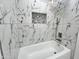 Close-up of a shower with marble-patterned tiles, shower niche, and modern fixtures at 22261 W Tonto St, Buckeye, AZ 85326