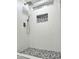 Contemporary shower with textured tile, pebble floor, and recessed shelf with pebble accent at 22261 W Tonto St, Buckeye, AZ 85326